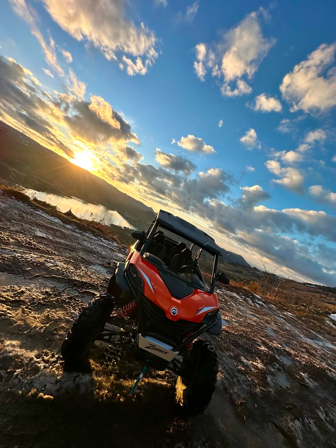 Buggy portocaliu la Colibița, la apus, cu lacul și cerul spectaculos în fundal